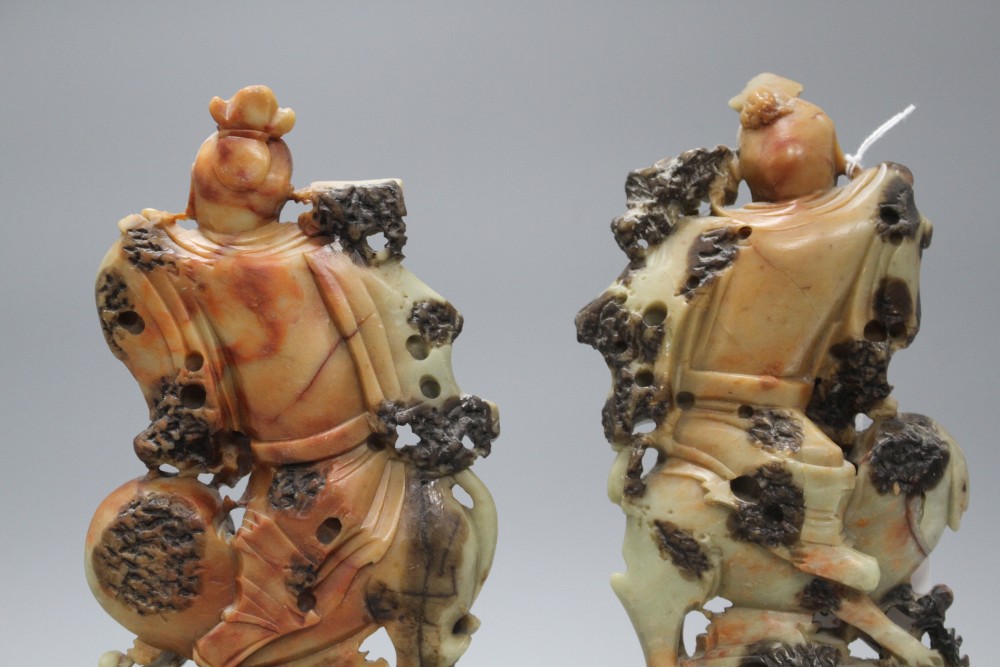 A pair of Chinese soapstone carvings depicting figures riding upon elephants, height 19cm, height with bases 27cm